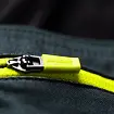 Detailní záběr na žlutý jezdec zipu s nápisem Arcteryx na tmavém textilním pozadí.