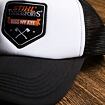 Šedá a bílá kšiltovka s černou síťovinou a nášivkou, na které je nápis "STIHL TIMBERSPORTS KISS MY AXE" a symboly dvou zkřížených sekyr.