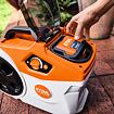 Ruka vkládá nebo vyndává baterii STIHL z kompaktního zahradního elektrického zařízení s ovládacím kolečkem a tlačítkem zapnutí.