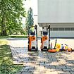 Dva stojící vysokotlaké čističe se značkou STIHL na dlažbě před garáží, doplněné o různé nástavce a čisticí prostředky vedle nich.