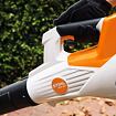 Ruka v rukavici drží zahradní elektrický foukač listí značky STIHL model BGA 50.