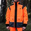 Muž v bezpečnostním oděvu určeném pro práci v lese, zahrnujícím reflexní oranžovou bundu s černými detaily a odpovídající kalhoty.
